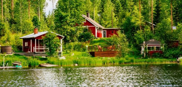 A traditional Finnish wooden cottage with a sauna and a barn on the lake shore. Summer rural Finland.