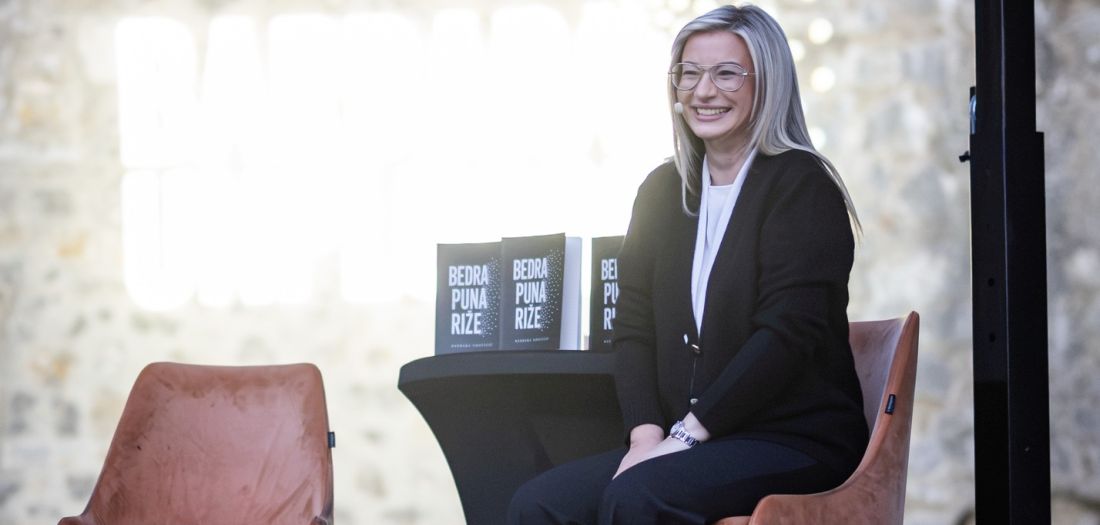 Barbara Udovicic sjedi ispred publike promocija knjige